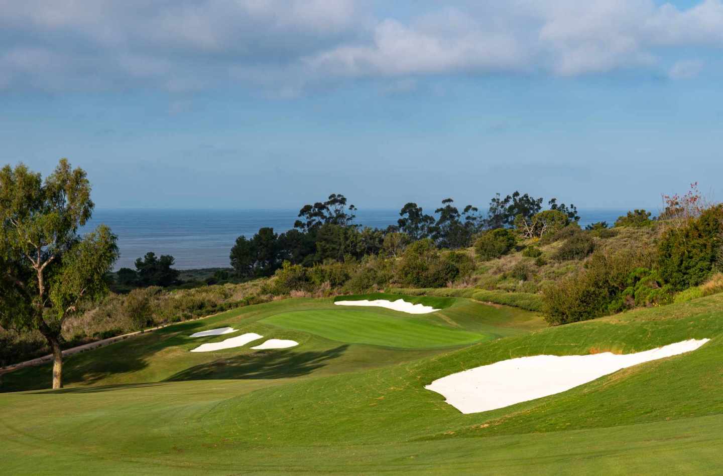 Restored first hole at Pelican Hill Ocean South, with white bunkers and a green overlooking the Pacific.