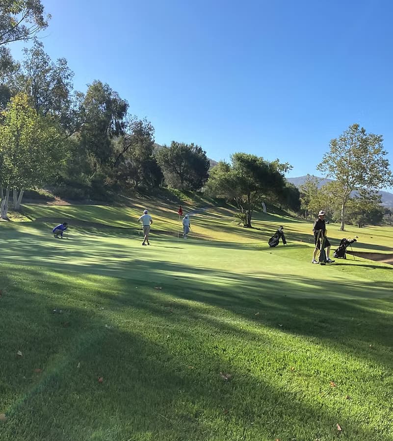 Golfers on a tree-lined green at The Havens Country Club.