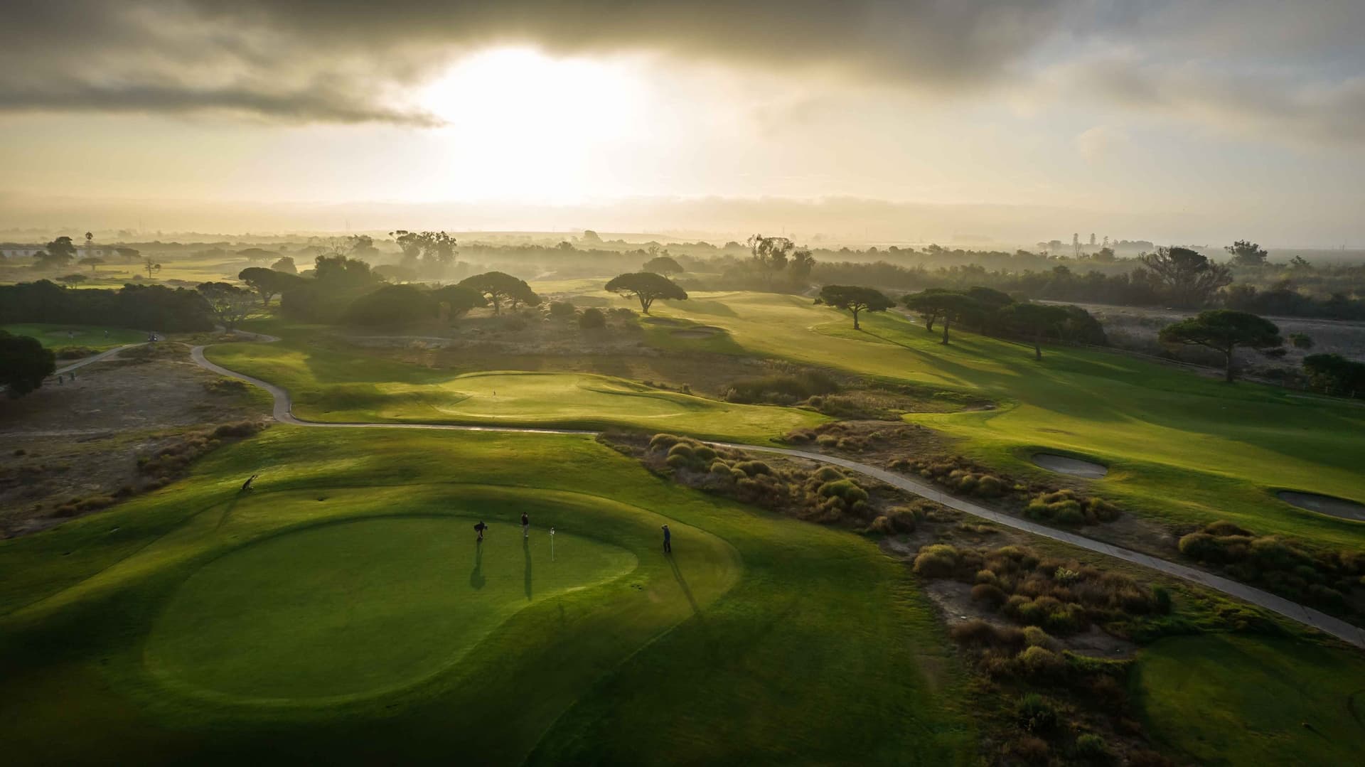 Golden-hour aerial over Olivas Links fairways and native grasses in Ventura.
